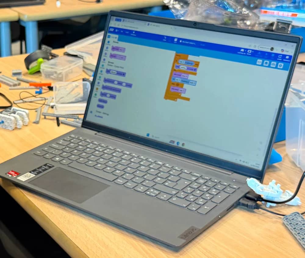A laptop displaying VEXcode blocks on a robotics workbench