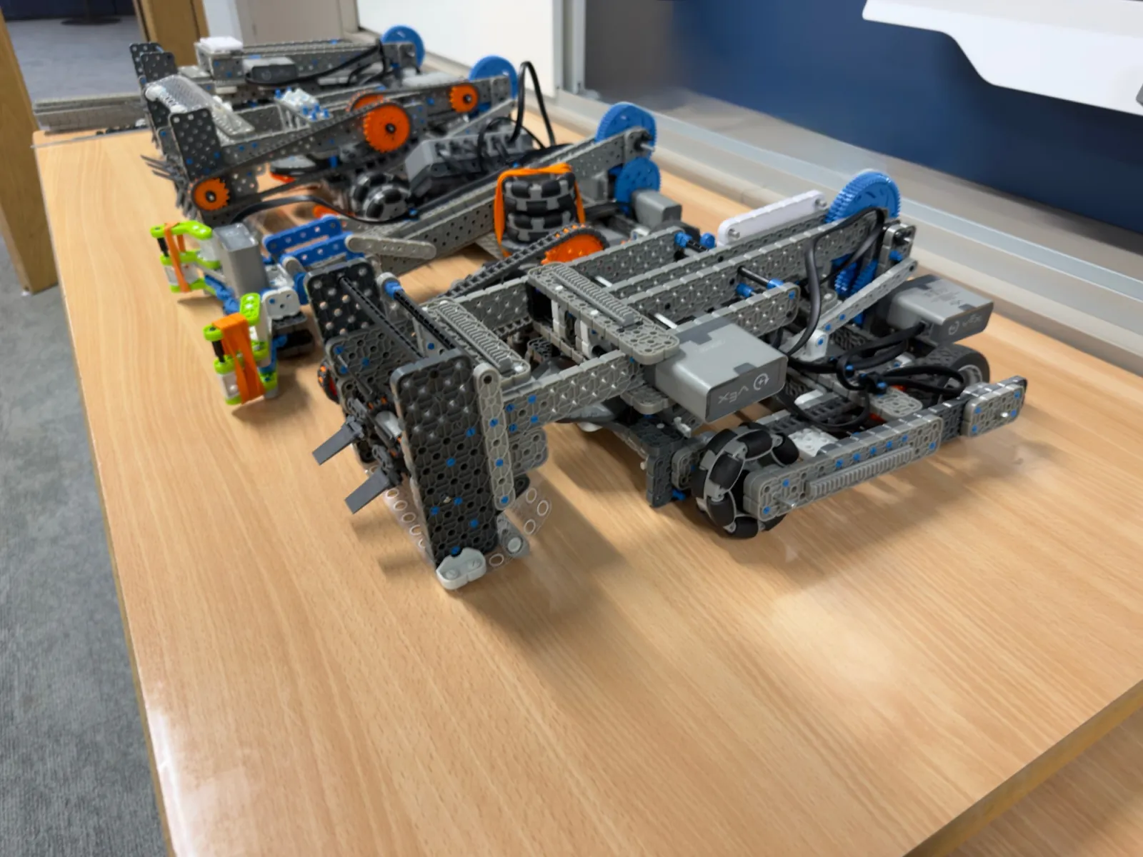 VEX IQ robots with lifting arms lined up on a classroom table
