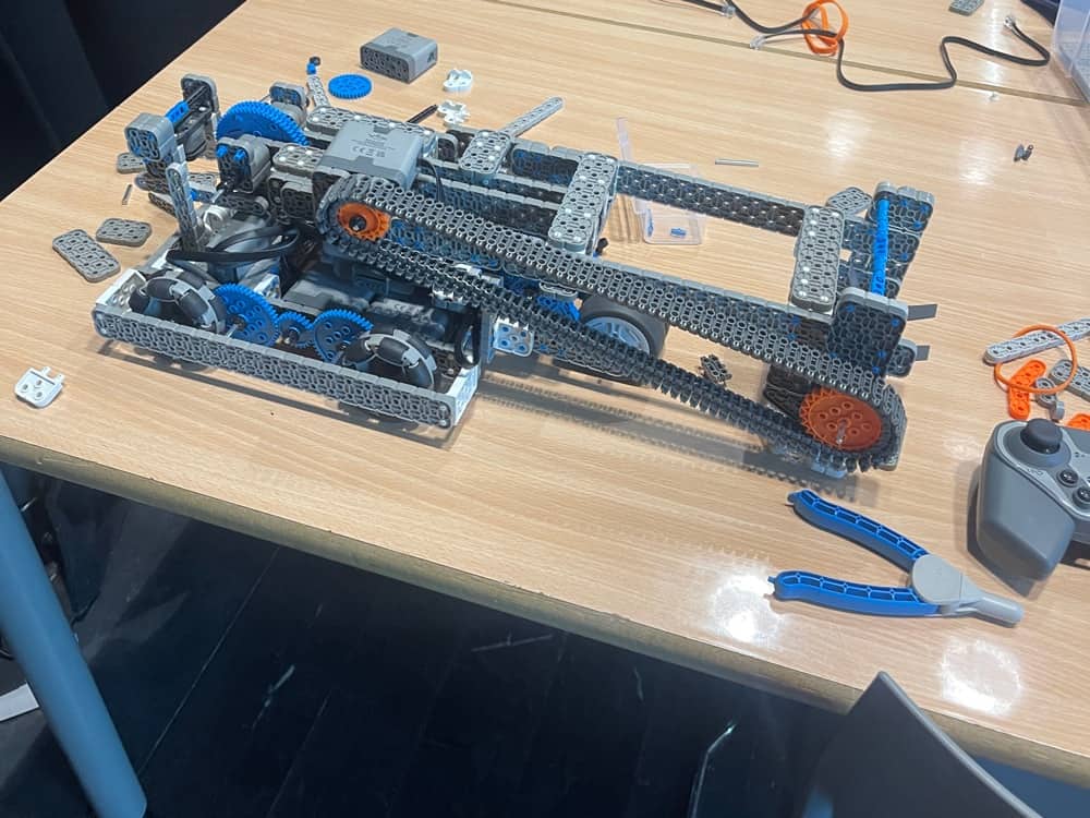 A part-built VEX IQ robot beside pliers and a controller