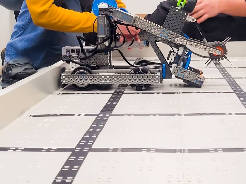 A VEX IQ robot with a lifting arm running on the game field