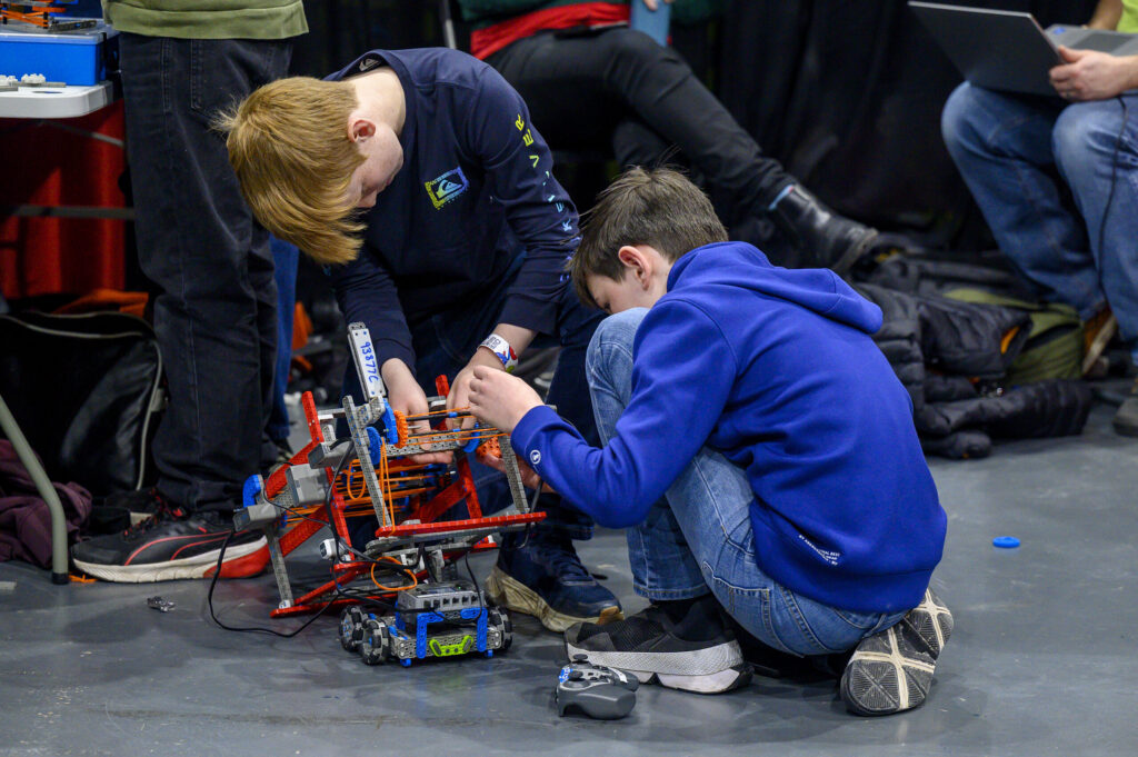 Young engineers making adjustments to a VEX competition robot